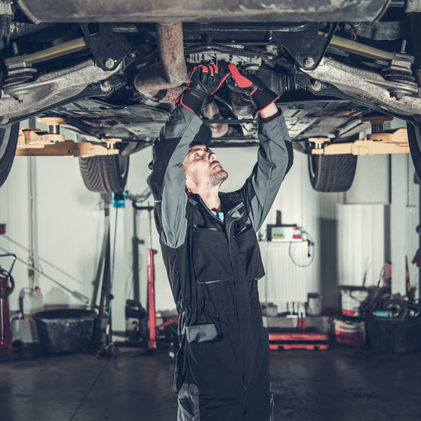 mechanic inspecting underbody of car